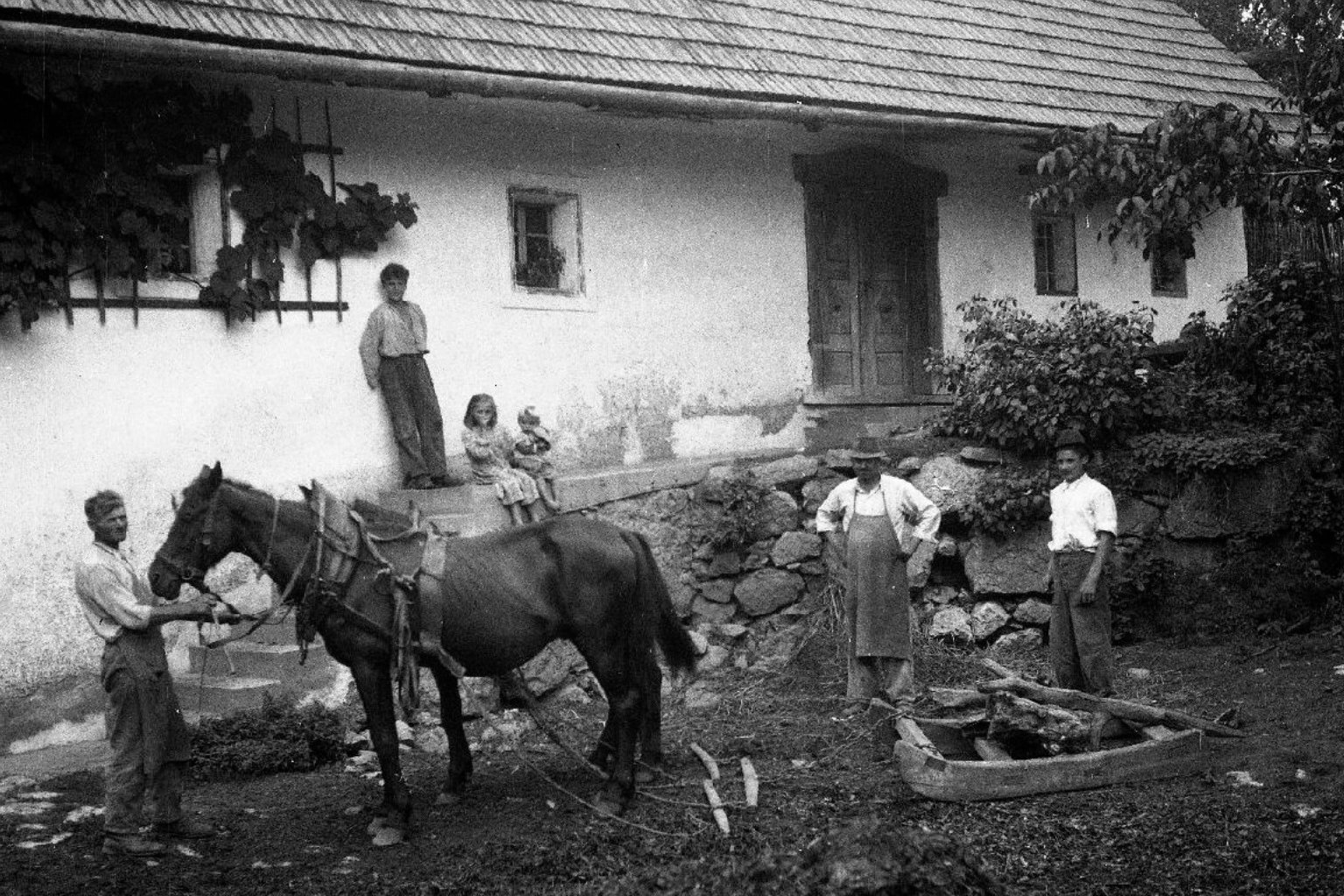 Slovenian family standing in front of a traditional homestead in Dolenjska, illustrating house name tradition