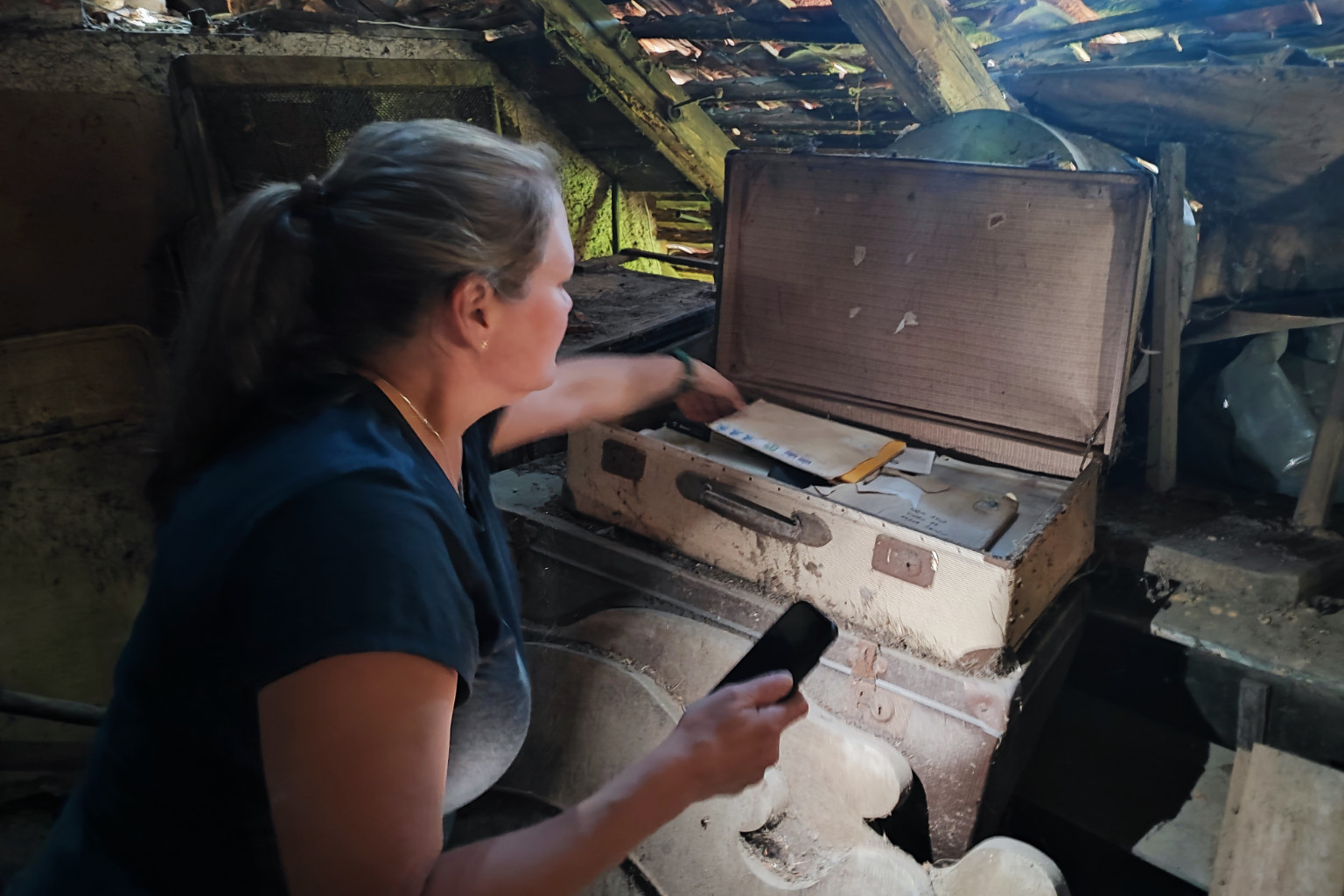 Pam Cesen exploring historic family artifacts in an ancestral homestead attic during a genealogy tour in Slovenia